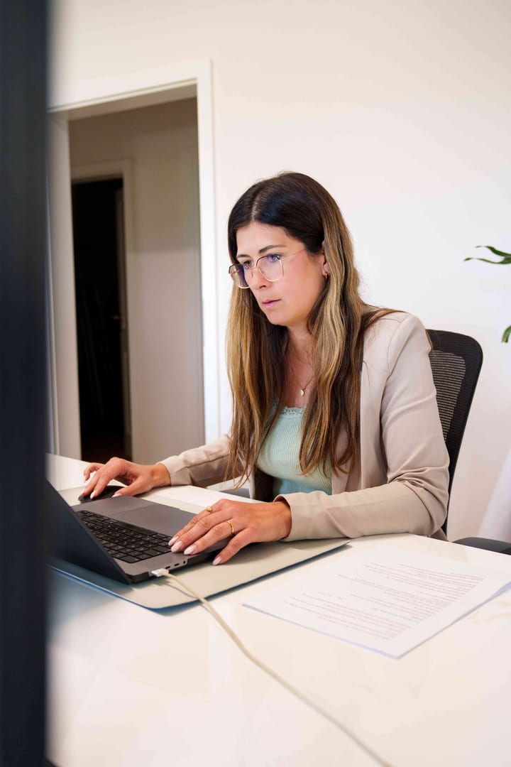 MediaOne Mitarbeiterin arbeitet konzentriert mit Brille am Laptop im Büro